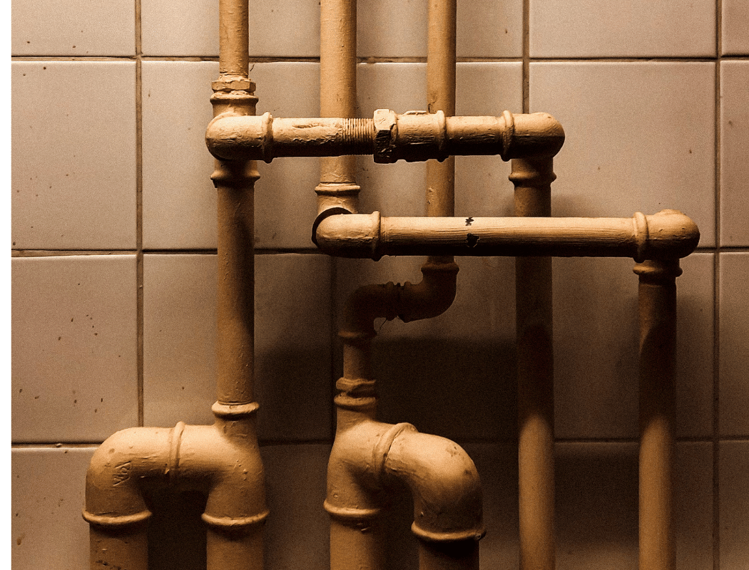 plastic vs copper pipes - older painted metal pipework running up a tiled wall (MCR Leak Detection)