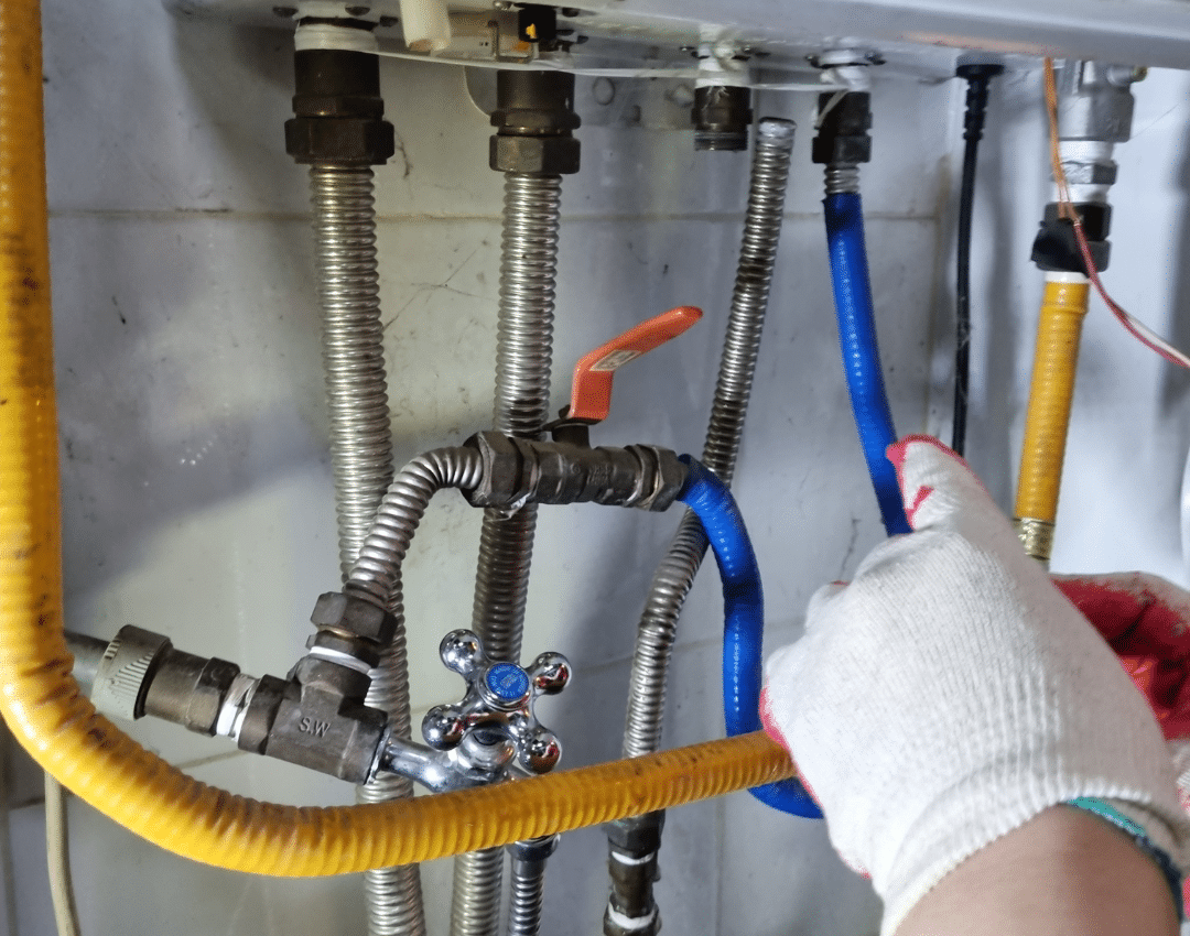 pressure relief valve leaking - gloved hand checking the valves and filling loop under a boiler (MCR Leak Detection)