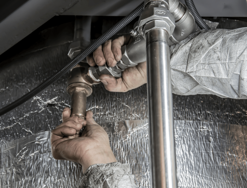 rodent damage pipes - engineer's hands checking pipework in an insulated under-floor void (MCR Leak Detection)